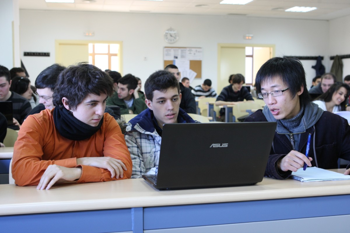 Trabajo de Fin de Máster – EMSE - UPM. Imagen de un grupo de tres estudiantes internacionales trabajando en un ordenador portátil en medio de una clase.