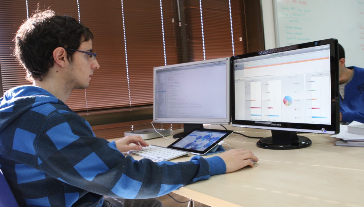 Máster Oficial en Ingeniería del Software. Imagen de un estudiante de la Escuela Técnica Superior de Ingenieros Informáticos trabajando ante dos pantallas de ordenador.